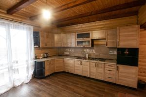 a kitchen with wooden cabinets and a large window at Котедж ВІКТОРІЯ in Bubnyshche