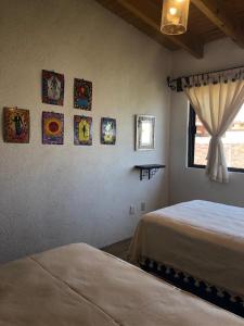 a bedroom with two beds and paintings on the wall at CASA FRIDA, Casa p/6 pax Centro Tequisquiapan in Tequisquiapan