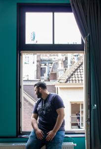a man sitting in front of a window looking out at Amsterdam Hostel Leidseplein in Amsterdam