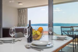 einen Tisch mit Gläsern und Tellern sowie eine Flasche Wein in der Unterkunft Abalone Apartments in Dramalj