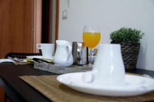 a glass of orange juice sitting on a table with a plate at Giulia's house apartments in SantʼAntonio Abate