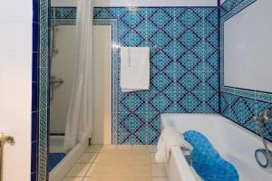 a blue tiled bathroom with a tub and a shower at Villa Phoenicia in Hammamet +37 photos