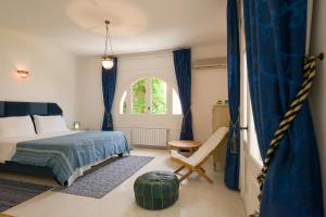 a bedroom with a bed and a chair and a window at Villa Phoenicia in Hammamet