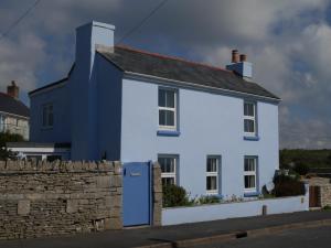 ein weißes Haus mit einer blauen Tür und einer Steinmauer in der Unterkunft Fishermans Cottage in Portland