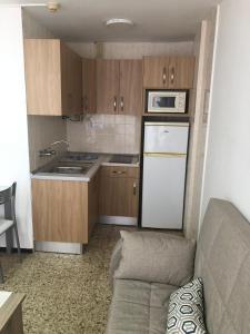 een kleine keuken met een bank en een witte koelkast bij Apartamentos Teror - Gavias del Sol in Playa del Inglés