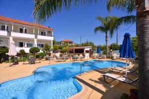 a pool with chairs and umbrellas next to a hotel at Theoxenia Hotel Apartments in Chrani