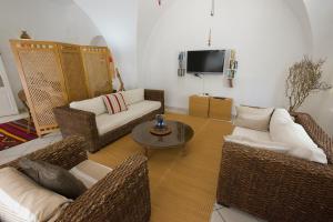 a living room with wicker furniture and a tv at Villa Phoenicia in Hammamet