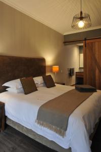 um quarto com uma grande cama branca e uma cabeceira castanha em Kestell Stables em Bloemfontein