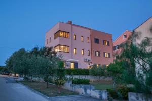a pink building with lights in the windows at Apartments Luana with private jacuzzi in Zadar