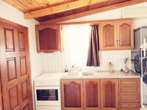 cocina con armarios de madera, fregadero y ventana en Dreamhome -10min from airport- en Artemida