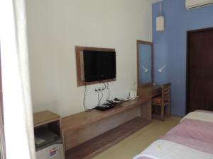 a bedroom with a tv on the wall and a bed at Casus Dream Hotel in Gili Trawangan