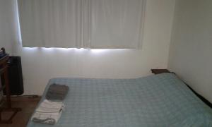 1 dormitorio con 1 cama con manta azul y ventana en Apart Altos Del Bolson en El Bolsón