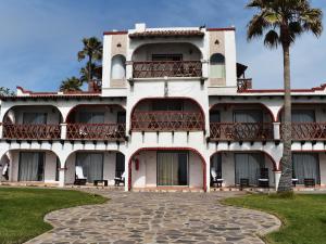 a large white building with balconies and a palm tree at Castillos Del Mar in Rosarito