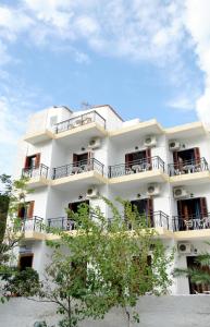 un edificio blanco con balcones y árboles en Hotel Rena, en Agios Kirykos