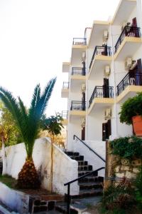 a building with stairs and a palm tree in front of it at Hotel Rena in Agios Kirykos