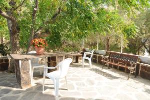 een patio met 2 stoelen, een tafel en banken bij Hotel Rena in Agios Kirykos