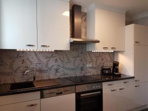 eine Küche mit weißen Schränken und einer schwarzen Arbeitsplatte in der Unterkunft A&M Apartment Bad Mergentheim in Bad Mergentheim