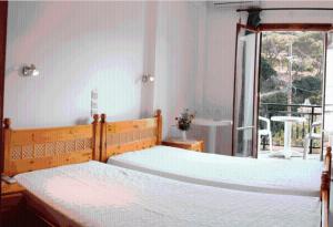 a bedroom with two beds and a large window at Hotel Rena in Agios Kirykos