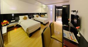 チェンナイにあるHotel Gokulam Parkのベッド2台とテレビがあるホテルの部屋