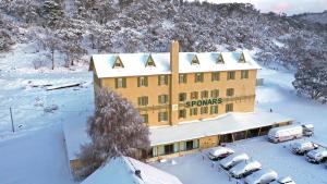 un edificio coperto da neve con auto parcheggiate nella neve di Sponars Chalet a Perisher Valley