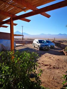 dos autos estacionados en un estacionamiento en el desierto en Hostal Katari, en San Pedro de Atacama