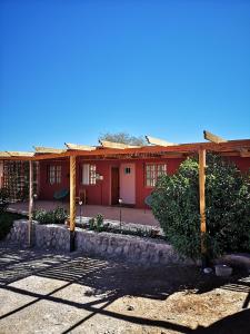 una casa roja con una valla delante en Hostal Katari, en San Pedro de Atacama