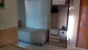 a small bedroom with a bed and a refrigerator at Golden Dolphin Express Roberto imoveis in Caldas Novas