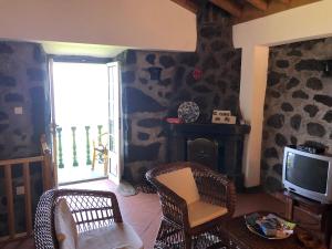 a living room with a tv and chairs and a fireplace at Casa de Lá in Prainha de Cima