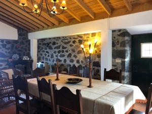 uma sala de jantar com uma mesa e uma parede de pedra em Casa de Lá em Prainha de Cima