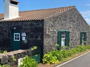 een oud stenen huis met groene deuren en een raam bij Casa de Lá in Prainha de Cima