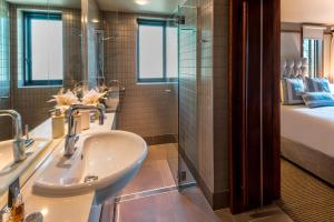a bathroom with a sink and a shower and a bed at Yacht Club Villas on Hamilton Island by HIHA in Hamilton Island