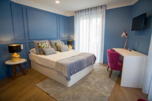 a blue bedroom with a bed and a window at ZIGZAG HOSTEL in Praia da Vitória