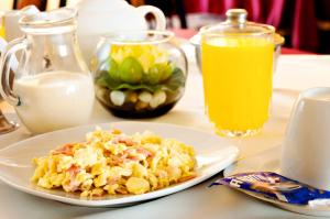 a plate of food on a table with milk and orange juice at Hotel Olaya in Lima