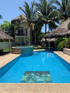 a pool in front of a house with palm trees at Playa Bruja Zicatela in Puerto Escondido