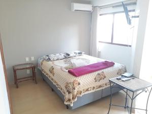 a bedroom with a bed with a table and a window at Wall Street Flat in Caxias do Sul
