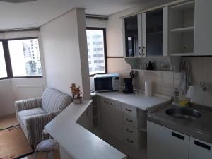 a small kitchen with a sink and a microwave at Wall Street Flat in Caxias do Sul