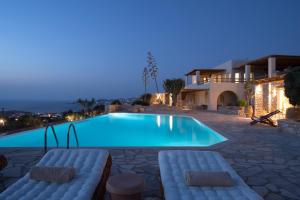 a beach with a pool, chairs, and a table at Mythic Paros , Adults Only in Agia Irini Paros