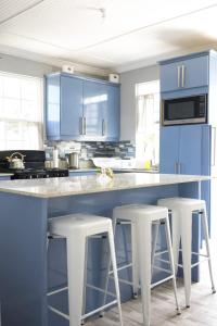 a kitchen with blue cabinets and white stools at Carmen Apartment in Bridgetown