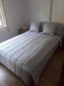 ein großes Bett in einem Schlafzimmer mit einer Bettdecke und Kissen in der Unterkunft Habitación JC in Madrid