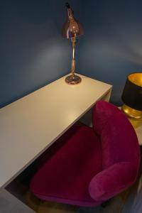 a red chair sitting under a table with a lamp at ZIGZAG HOSTEL in Praia da Vitória