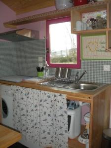 eine kleine Küche mit einem Waschbecken und einem Fenster in der Unterkunft Le Gît´an Roulotte in Bessey
