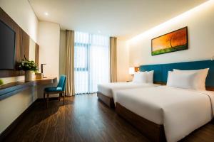 A bed or beds in a room at Maximilan Danang Beach Hotel