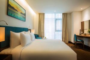 A bed or beds in a room at Maximilan Danang Beach Hotel