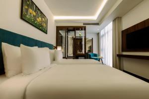 A bed or beds in a room at Maximilan Danang Beach Hotel