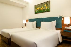 A bed or beds in a room at Maximilan Danang Beach Hotel