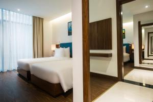 A bed or beds in a room at Maximilan Danang Beach Hotel