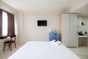 a white bedroom with a large bed and a desk at Cozy Studio with City View at Elvis Tower Apartment By Travelio in Cikarang +3 photos