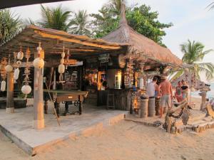 a bar on the beach with people standing in front of it at Coco Lanta Resort - SHA Extra Plus in Ko Lanta