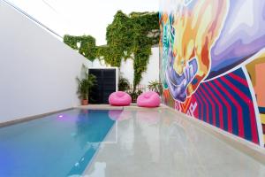 a swimming pool with pink chairs next to a mural at Great Villas estudios & residences - THE KAHLO in Playa del Carmen