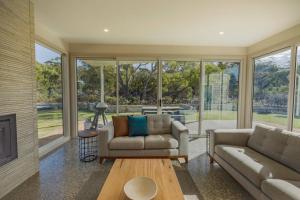 a living room with two couches and a fireplace at Baileys Beach House in Binalong Bay